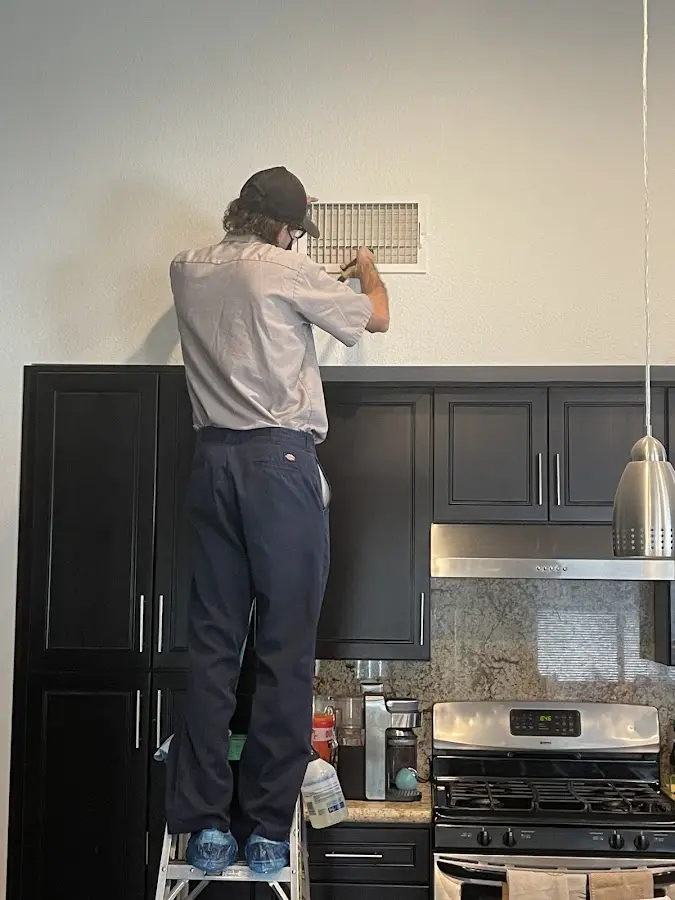 Technician inspecting an air vent during HVAC service in San Antonio